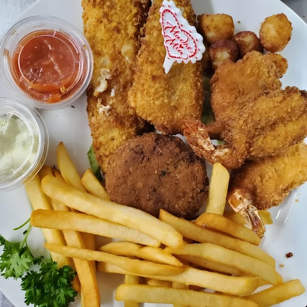 Quickway Diner's fried seafood platter with shrimp, fish, crab cake, scallops, fries, and dipping sauces.