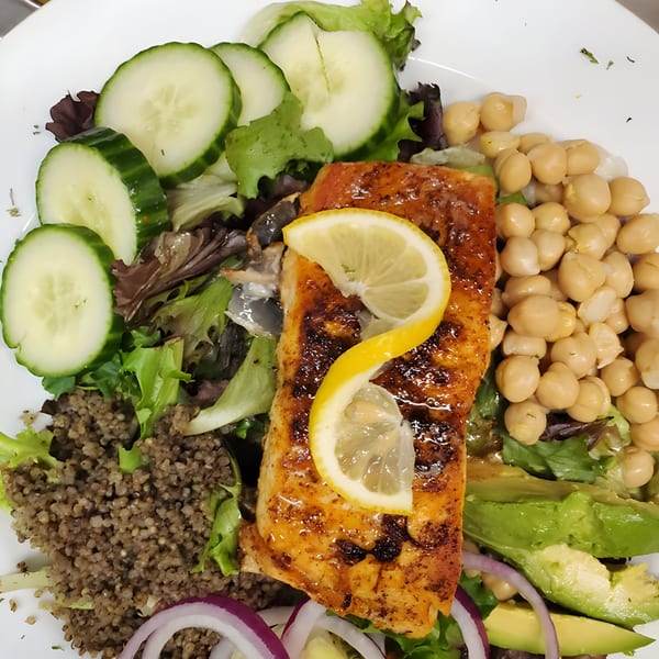 Quickway Diner's grilled salmon with lemon slices, chickpeas, avocado, quinoa, and a fresh salad.