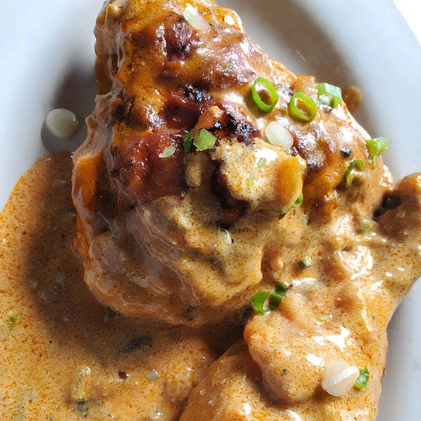 Close-up of Quickway Diner's creamy chicken dish, garnished with chopped green onions and white onions.